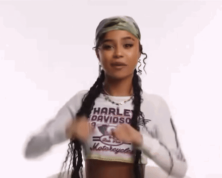 A Woman Wearing A Harley Davidson Shirt Is Holding Her Hair In Pigtails . GIF
