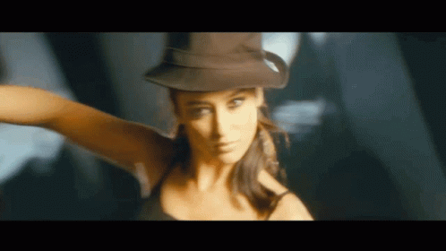 A Woman Wearing A Hat And A Black Tank Top Is Dancing GIF