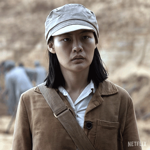 A Woman Wearing A Hat And A Brown Jacket With A Netflix Logo In The Corner GIF