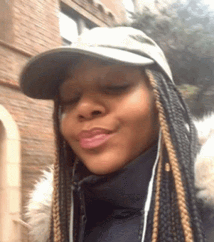 A Woman Wearing A Hat And A Jacket Is Making A Face . GIF