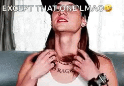A Woman Wearing A Hat And A Necklace Is Sitting On A Couch And Scratching Her Neck . GIF