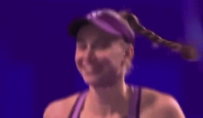a woman wearing a hat and a purple tank top is smiling .