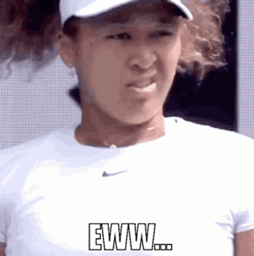 A Woman Wearing A Hat And A White Shirt Is Making A Funny Face And Says Eww . GIF