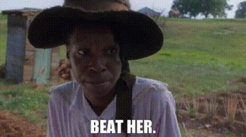 A Woman Wearing A Hat And A White Shirt Is Standing In A Field With The Words `` Beat Her '' . GIF