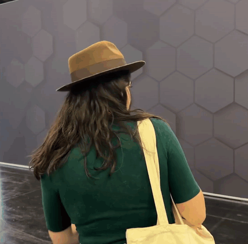 A Woman Wearing A Hat And Carrying A Bag GIF