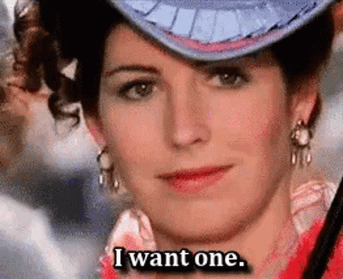 A Woman Wearing A Hat And Earrings Is Saying I Want One . GIF