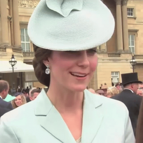 A Woman Wearing A Hat And Earrings Is Smiling GIF