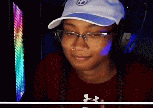 A Woman Wearing A Hat And Glasses Is Smiling And Wearing An Under Armour Shirt GIF