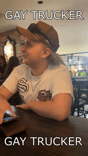 A Woman Wearing A Hat And Sunglasses Is Sitting At A Table With The Caption Gay Trucker Gay Trucker GIF