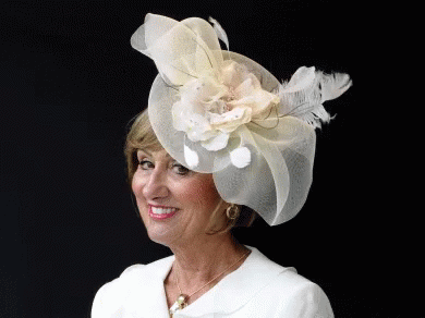 A Woman Wearing A Hat With A Flower And Feathers GIF