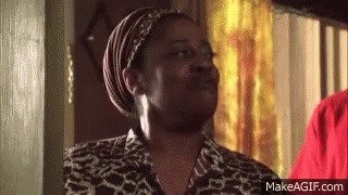 A Woman Wearing A Head Scarf And A Leopard Print Shirt Is Standing In A Room . GIF