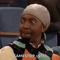 A Woman Wearing A Head Scarf And A Sweater Is Sitting In A Classroom . GIF