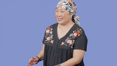 A Woman Wearing A Head Scarf Is Standing In Front Of A Sign That Says Oops GIF