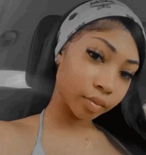 A Woman Wearing A Headband And A Necklace Is Sitting In A Car And Looking At The Camera . GIF