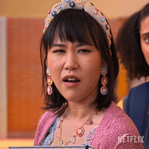 A Woman Wearing A Headband And Earrings Is Making A Funny Face GIF