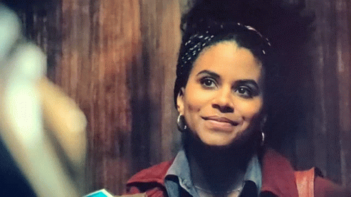 A Woman Wearing A Headband And Earrings Is Smiling . GIF