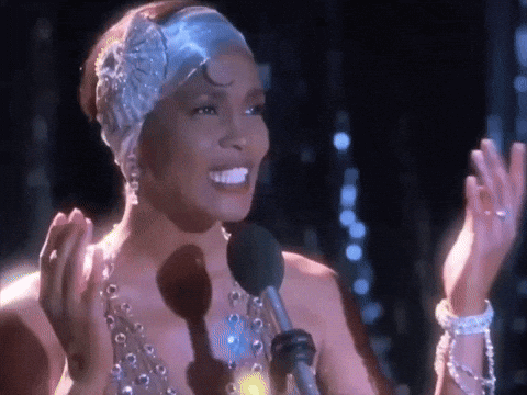 a woman wearing a headband and pearls is singing into a microphone .