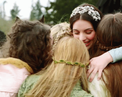 A Woman Wearing A Headband With Flowers On It Is Hugging Three Other Women GIF