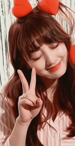 A Woman Wearing A Headband With Hearts On It Is Giving A Peace Sign GIF
