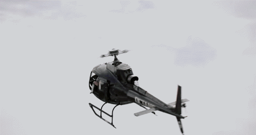 A Woman Wearing A Headset And Gloves Looks Out Of A Helicopter Window GIF