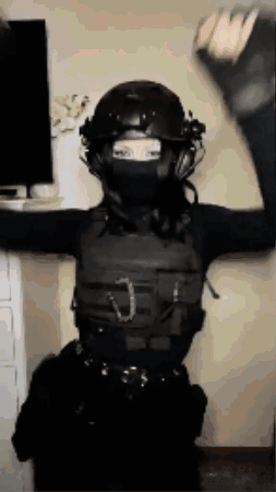 A Woman Wearing A Helmet And A Mask Is Standing In Front Of A Television . GIF