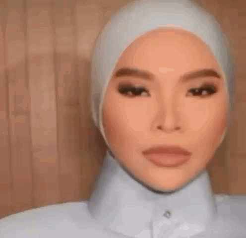 A Woman Wearing A Hijab And A White Shirt Is Smiling . GIF
