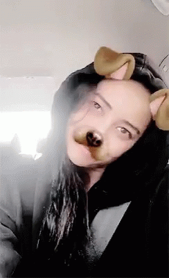 A Woman Wearing A Hooded Jacket And Dog Ears Looks At The Camera . GIF