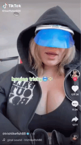 A Woman Wearing A Hoodie And A Blue Visor Is A Tiktok Video . GIF