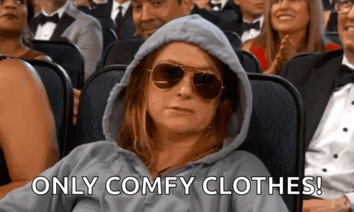 a woman wearing a hoodie and sunglasses is sitting in a theater .