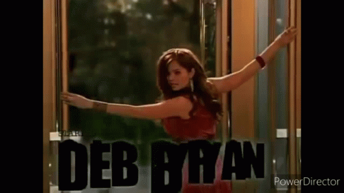 A Woman Wearing A Hoodie With The Name Debby Ryan On It Is Standing In A Room . GIF