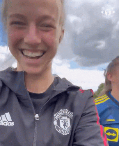 A Woman Wearing A Jacket That Says Manchester United On It GIF