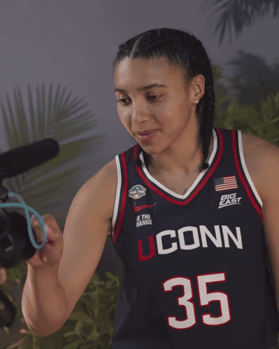 A Woman Wearing A Jersey That Says Uconn 35 On It GIF
