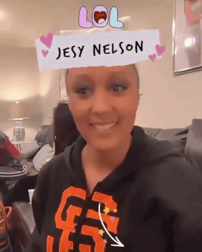 A Woman Wearing A Jesy Nelson Headband Smiles GIF