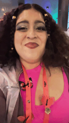 A Woman Wearing A Lanyard With A Butterfly On It And A Pink Top With A Butterfly Pin GIF