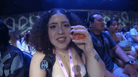 A Woman Wearing A Lanyard With The Letter E On It Holds Something In Her Hand GIF