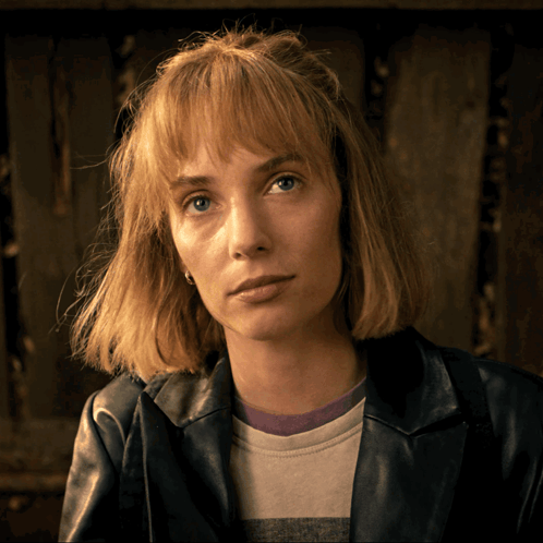 A Woman Wearing A Leather Jacket And A Striped Shirt Looks At The Camera GIF