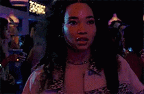 a woman wearing a leopard print jacket and a necklace is standing in a dark room .