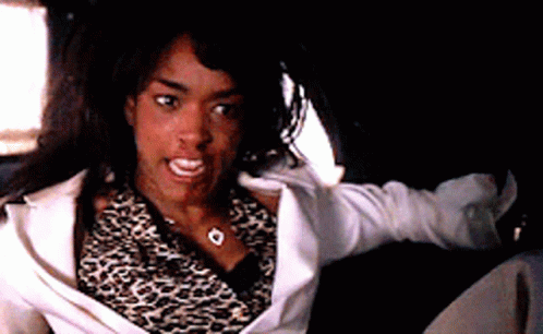 A Woman Wearing A Leopard Print Shirt And A White Jacket Is Sitting In A Car GIF