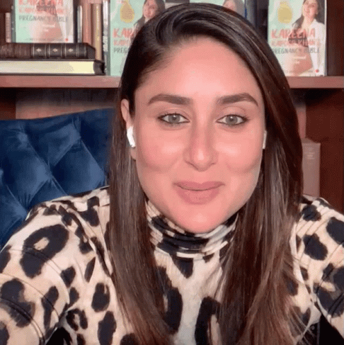 A Woman Wearing A Leopard Print Shirt Is Smiling In Front Of A Bookshelf With Kareena Kapoor Books GIF