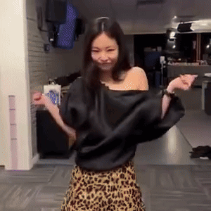 A Woman Wearing A Leopard Print Skirt And A Black Top Is Dancing In A Room . GIF