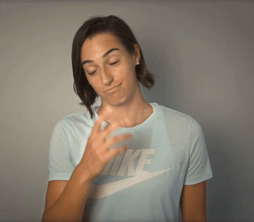 a woman wearing a light blue nike shirt is covering her face with her hand