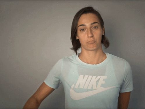 a woman wearing a light blue nike shirt makes a funny face