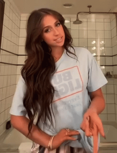 A Woman Wearing A Light Blue T-Shirt With The Word Big On It Is Standing In A Bathroom GIF