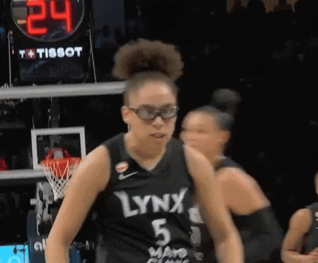 A Woman Wearing A Lynx 5 Jersey Stands In Front Of A Scoreboard GIF