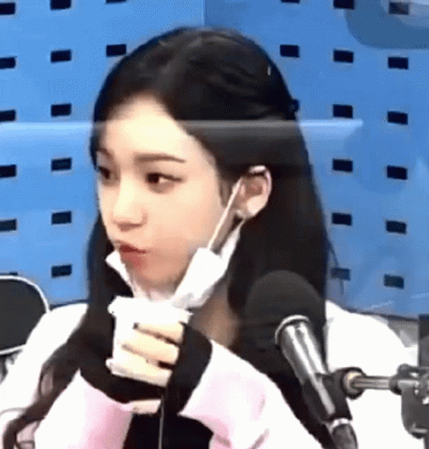 A Woman Wearing A Mask And Earphones Is Sitting In Front Of A Microphone . GIF