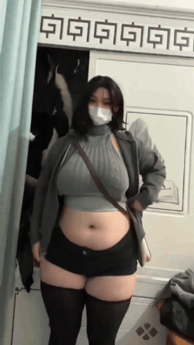 Woman In Mask And Shorts Standing In Front Of A Sign GIF