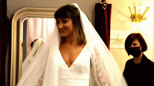 A Woman Wearing A Mask Is Standing Next To A Woman Wearing A Veil GIF