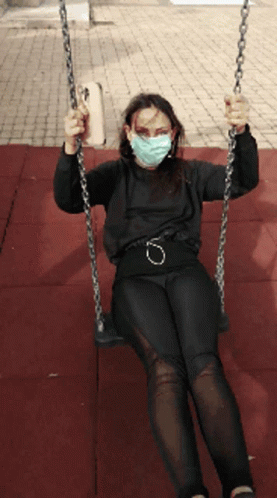 A Woman Wearing A Mask Is Swinging On A Chain GIF