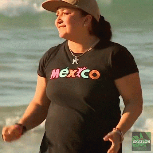 a woman wearing a mexico t-shirt is standing on the beach
