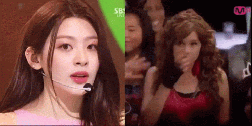 A Woman Wearing A Microphone And A Wig Is Standing Next To A Woman Wearing A Wig . GIF